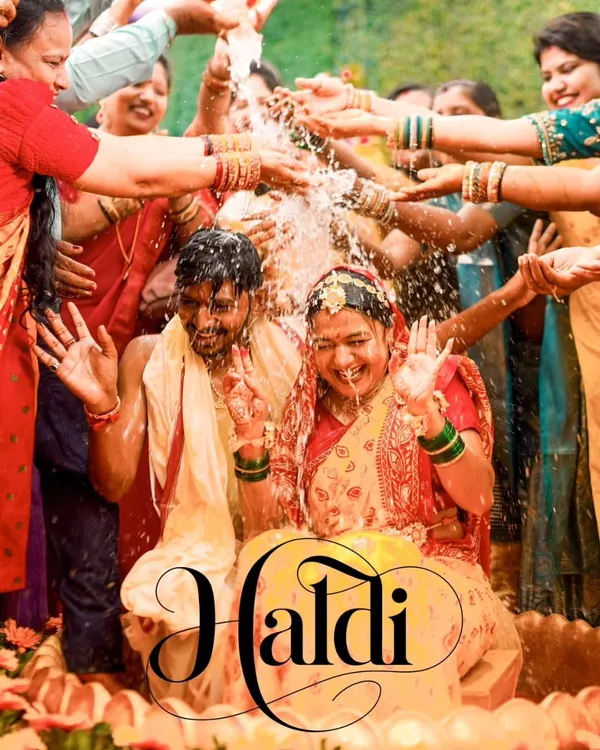 A quintessential Haldi shot, capturing the couple being showered with water and blessings by their loved ones. This image is all about pure, unadulterated joy.