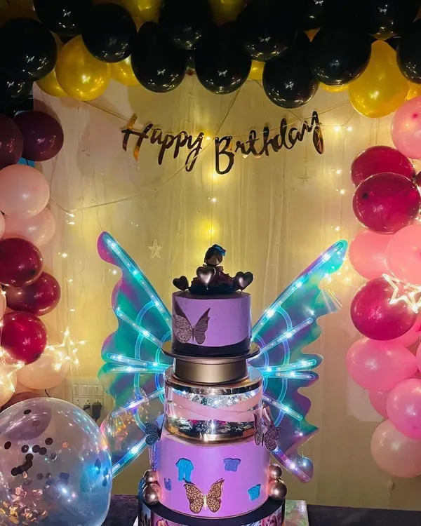 A full view of a custom butterfly wings cake set up for a party. The glowing wings and intricate details make it the perfect centerpiece, surrounded by balloons and party lights.