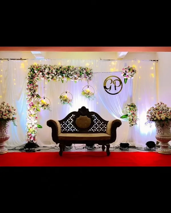 A classic reception stage setup featuring an L-shaped floral arch, hanging floral hoops, and elegant uplighting. This design is perfect for creating a sophisticated and romantic focal point for your event.