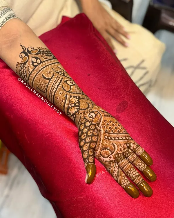 A full-arm bridal henna design that is all about detail. This piece combines classic Indian paisley, peacock feathers, and floral patterns for a rich and traditional look that extends up the forearm.