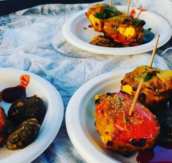 A plate of assorted tandoori appetizers, including paneer tikka and hara bhara kabab, served with mint chutney. A perfect starter for any event.