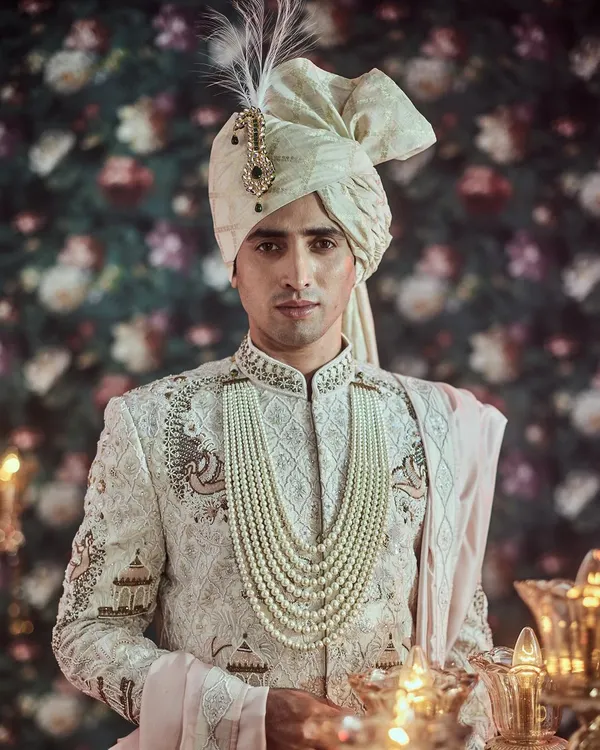 This exquisite sherwani showcases the pinnacle of our craftsmanship, featuring intricate hand embroidery on a pristine white base, perfect for a groom seeking timeless elegance.