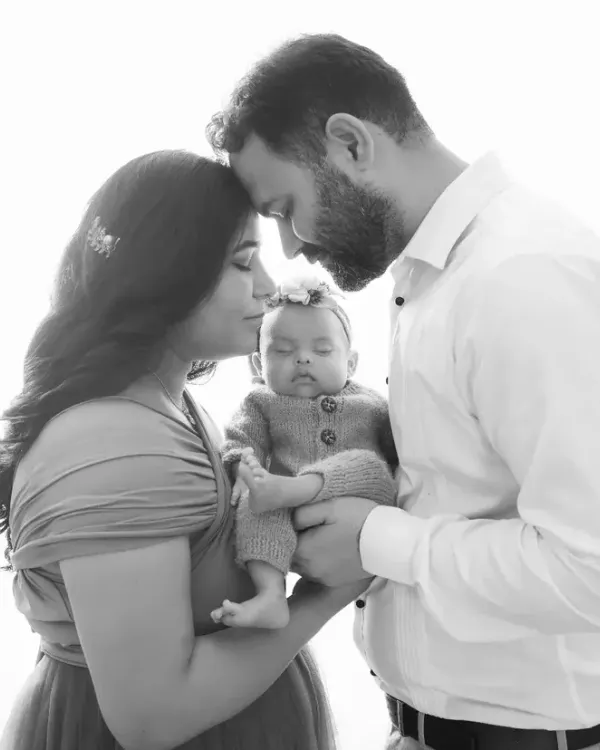 A beautiful black and white portrait of a new family. This pose, with parents kissing the baby's head, is a timeless way to show your love and affection.