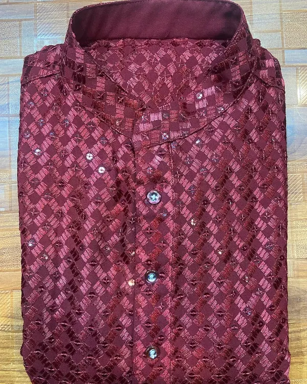 A festive men's kurta in a rich maroon, made from a patterned fabric with delicate sequin work. The mandarin collar and custom buttons complete this look, perfect for any celebratory event.