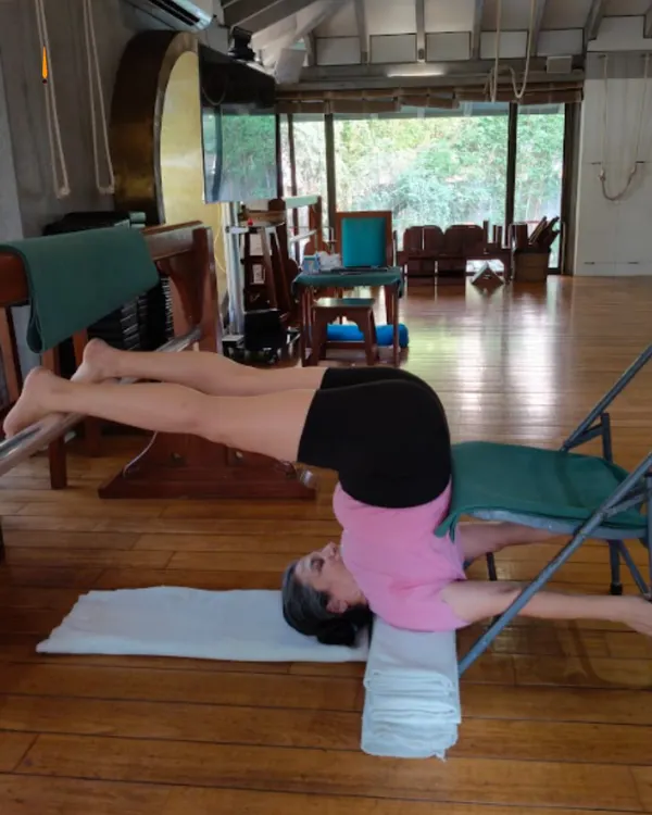 Using a chair and blankets for support in Halasana (Plough Pose) allows the student to hold the posture longer, calming the nervous system and releasing tension in the neck and shoulders without any strain. This is the intelligence of props.