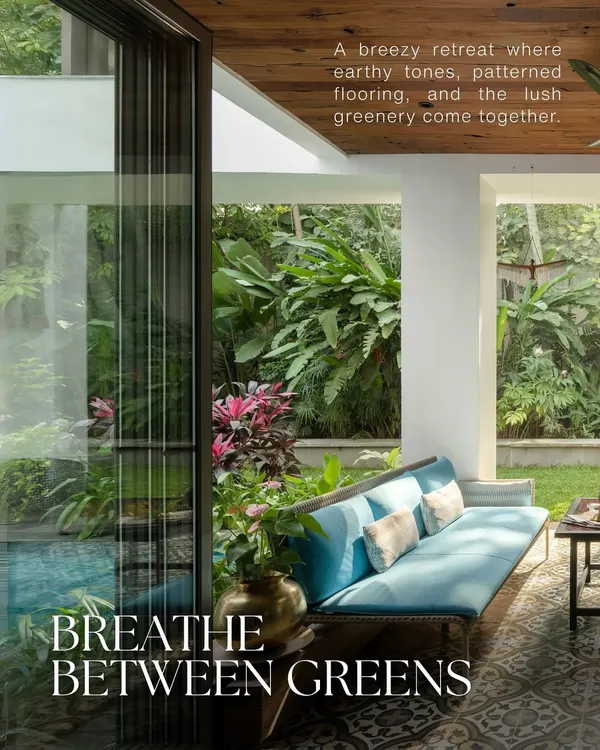 A breezy retreat where the garden flows indoors. The design uses patterned flooring and a wooden ceiling to create a dialogue between the custom blue sofa and the lush tropical plants, blurring the lines for true indoor-outdoor living.