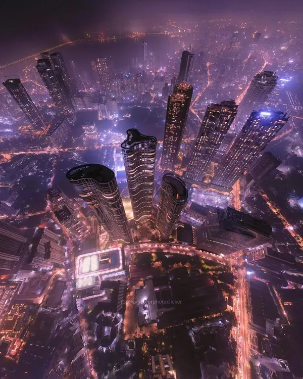 A stunning "little planet" style aerial photograph of Mumbai's skyscrapers at night, creating a dizzying and futuristic view of the city's vertical growth.