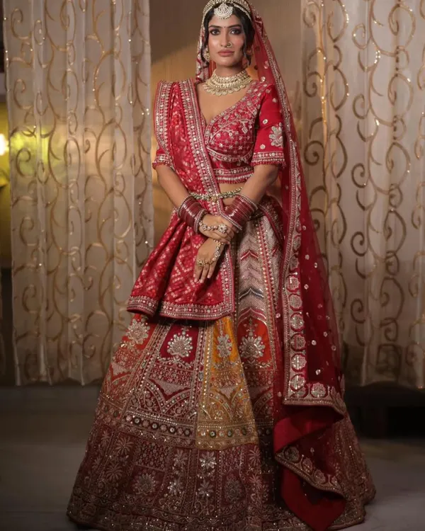 This multi-panelled bridal lehenga combines traditional red with shades of yellow and intricate silver embroidery. It's a perfect choice for the bride who wants a unique, vibrant, and classic look all in one.