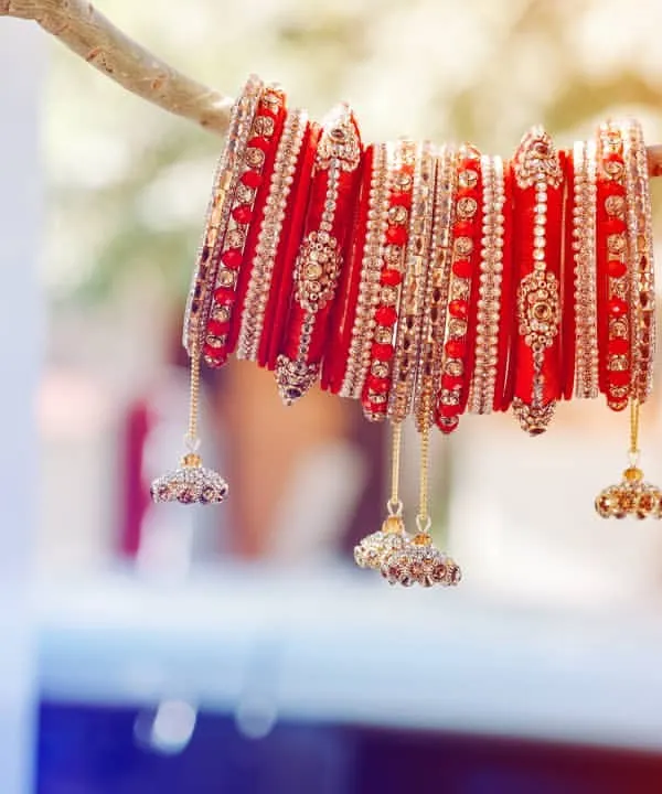 A creative shot of the bride's traditional red 'chura' (bangles). We love finding artistic ways to photograph these important symbols of a wedding, highlighting their beauty and significance.