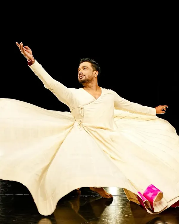 A powerful still from a Sufi dance piece, capturing the essence of spiritual surrender through movement. The flowing costume and expressive gesture are central to this form of dance.