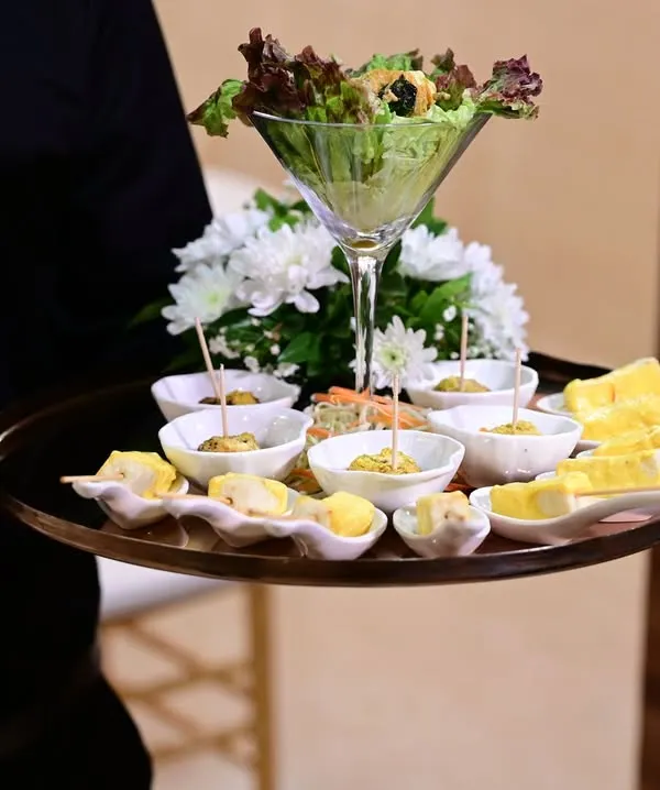 Our servers present elegantly arranged trays of appetizers, ensuring every guest is welcomed with a delicious bite. This tray features a variety of carefully crafted starters, including paneer skewers and salad cups.