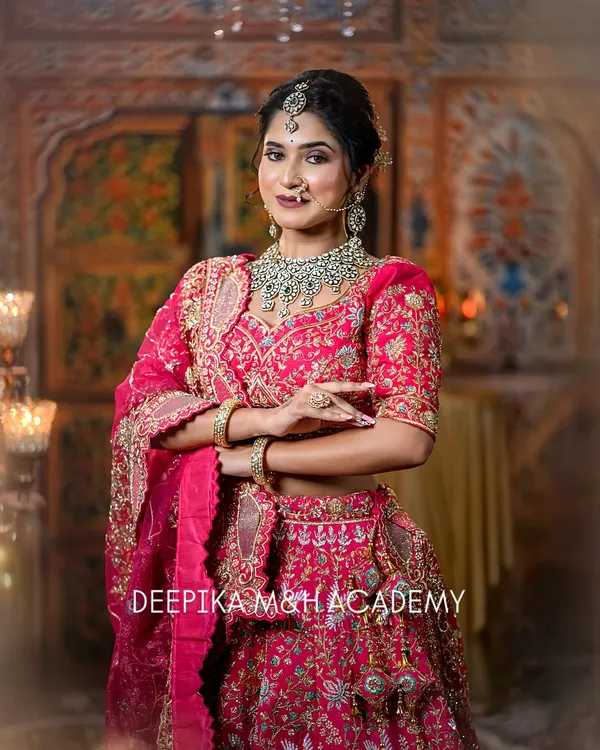 A stunning North Indian bride in a vibrant pink lehenga. The look is completed with a beautiful polki and emerald jewelry set and a soft, glamorous makeup look.