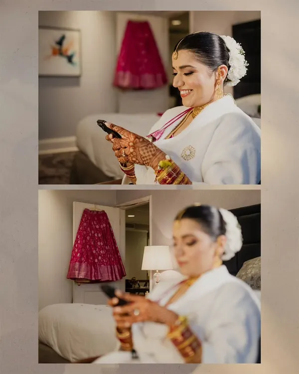 A candid moment of the bride-to-be, smiling as she looks at her phone. In the background, her vibrant pink wedding lehenga hangs, waiting for the ceremony to begin.