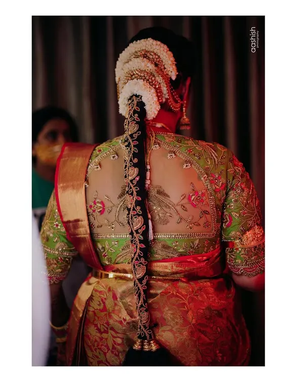 This blouse is a perfect example of my passion for detail. It features a sheer back with intricate zardosi work depicting birds on a branch, creating a stunning piece of wearable art for the bride's parrot green and red Kanjeevaram.