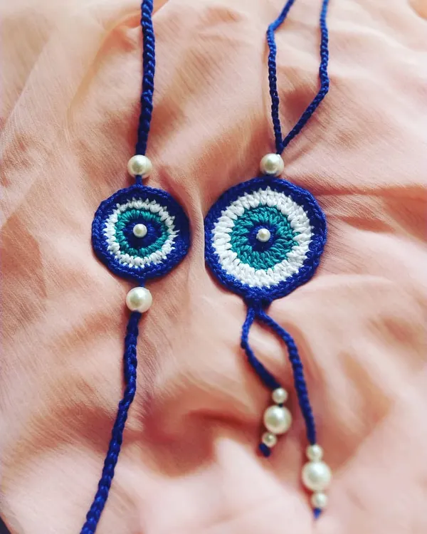 Our popular evil eye Rakhi and Lumba set for bhaiya and bhabhi. This handmade crochet duo is designed to be a symbol of protection and love, featuring pearl bead details on a durable thread.
