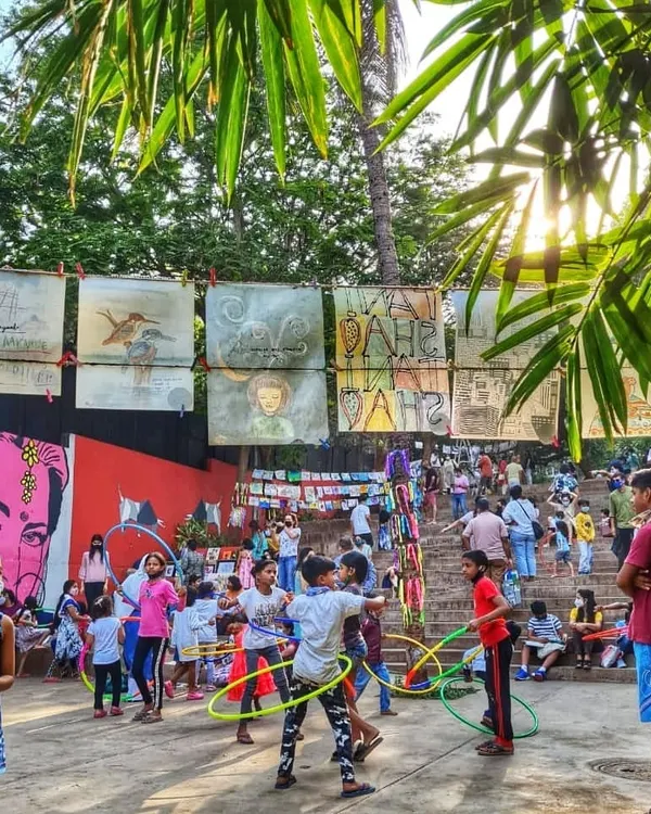 Children playing with hula hoops at The Steps, with community artwork displayed in the background. This space is designed for play, creativity, and connection, turning a forgotten corner of Bandra into a hub of activity.