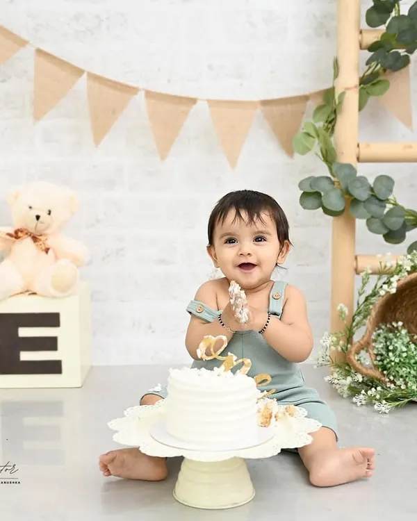That look of pure delight! This little one is enjoying every second of his first birthday cake smash. The simple, rustic setup with natural tones and a teddy bear keeps the focus on his happy expressions.
