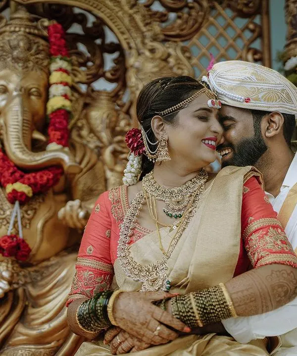 A quiet, happy moment between the bride and groom during their traditional South Indian wedding ceremony in Bangalore. I focus on capturing these genuine connections, blending candid photography with the richness of the cultural setting, like the ornate Ganesha sculpture in the background.