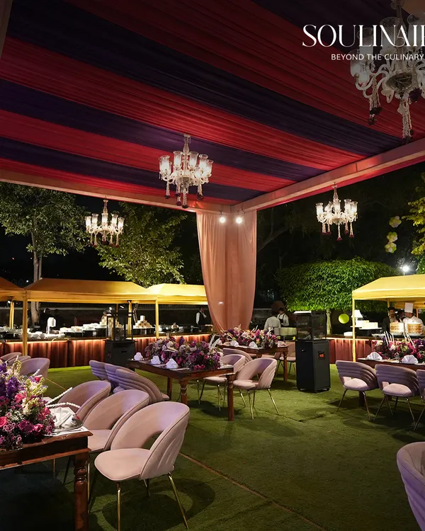 An enchanting outdoor wedding reception at dusk, with elegantly set tables under a canopy of chandeliers and lush greenery. We create magical settings for your most cherished moments.