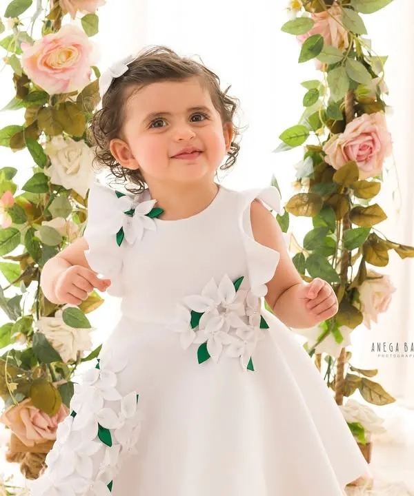 A beautiful portrait of a little girl on a floral swing. Her bright smile and the whimsical setup create a magical childhood memory.