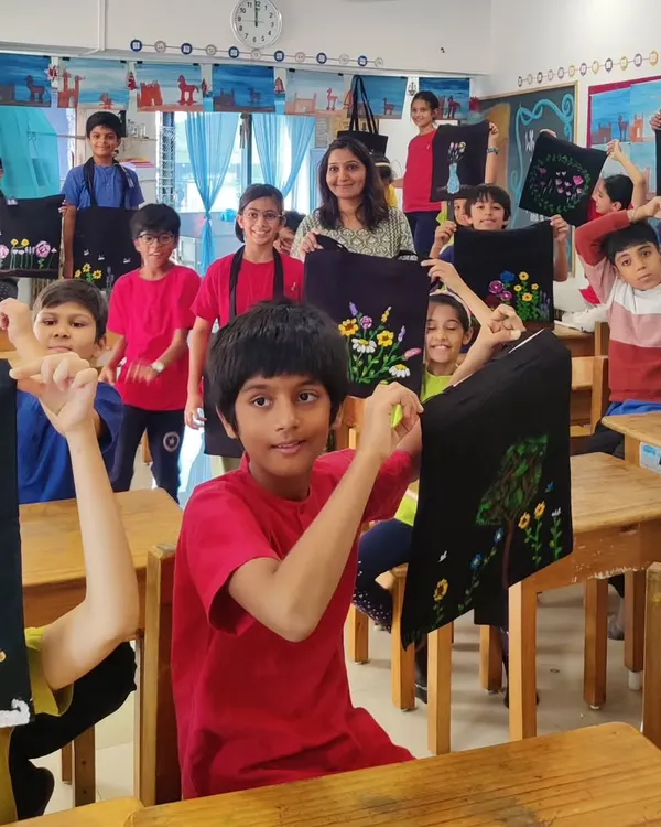 A classroom of students proudly showing off the tote bags they painted during a school workshop. Each bag is a canvas for their unique floral designs, creating a wonderful gallery of wearable art.
