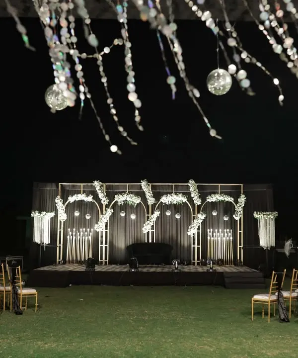 A wide shot of a glamorous black, white, and gold Sangeet stage. The setup includes a large dance floor and elegant seating, ready for a night of performances.