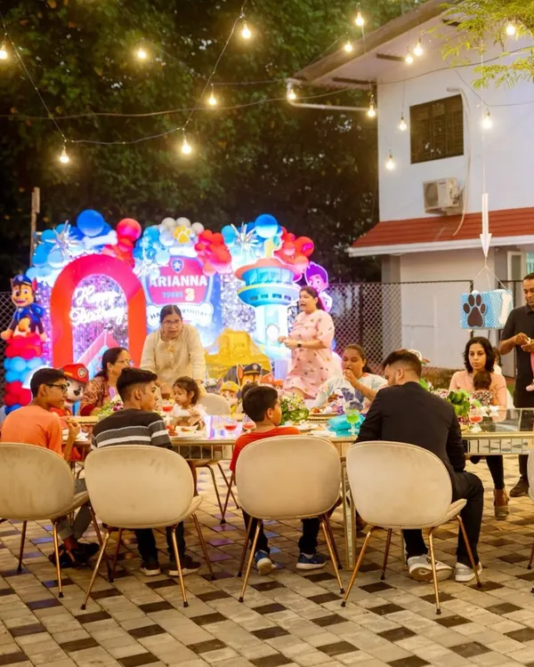 A happy family enjoying a meal at a child's third birthday party. The festive balloon decor and outdoor setting create a relaxed and joyful atmosphere for all the guests.