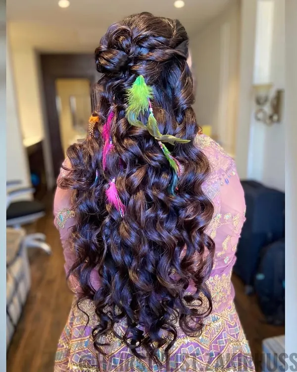 This is the ultimate boho-chic hairstyle for a Mehendi party. I created a half-updo with voluminous curls and added colorful feathers for a fun and free-spirited vibe.