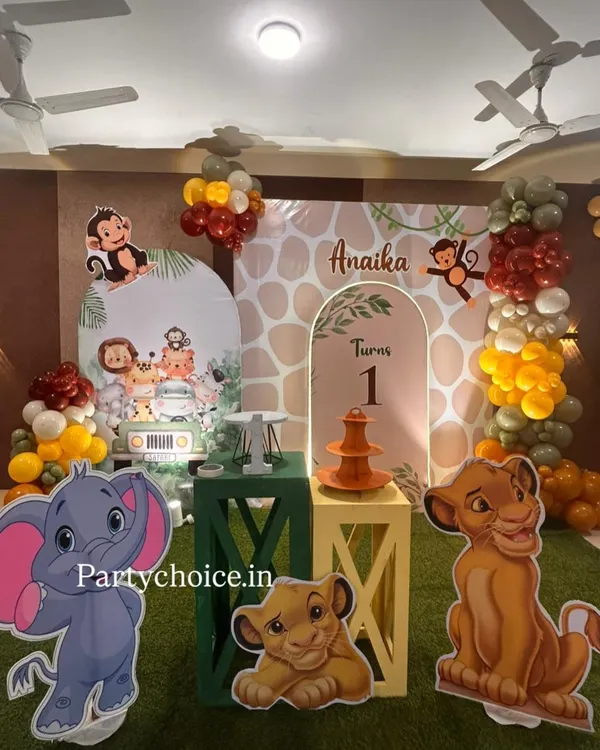 A complete jungle theme setup for a first birthday, featuring beloved characters from The Lion King and other animal friends. The decor includes a personalized backdrop, themed plinths, and character standees.