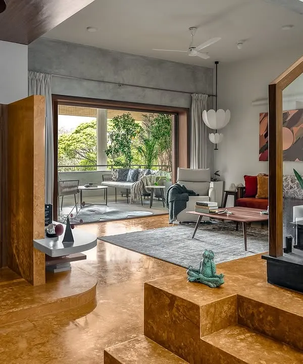 This living room combines earthy turmeric-colored flooring with cool grey concrete walls. The space opens onto a large balcony, demonstrating our principle of seamless indoor-outdoor living.
