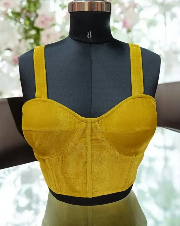 A velvet corset blouse is a perfect blend of elegance and modern style. This mustard yellow piece is structured to provide a beautiful shape and can be paired with sarees, skirts, or trousers.