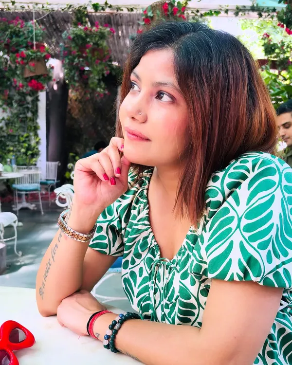 A close-up of the green and white leaf-print dress. The puff sleeves and delicate neckline add a soft, romantic touch to the vibrant pattern, perfect for a dreamy cafe afternoon.