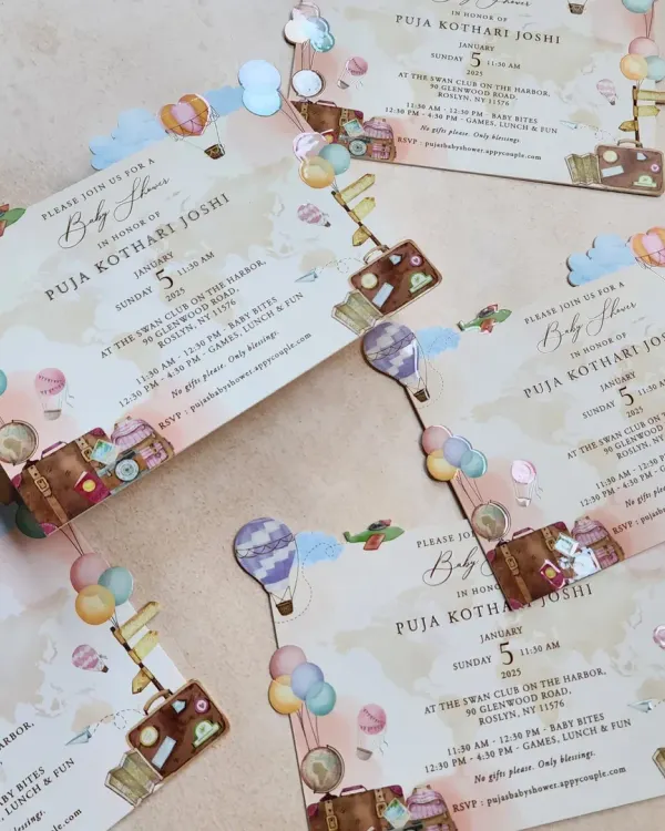 A whimsical travel-themed baby shower invitation. We used custom illustrations of hot air balloons, suitcases, and airplanes with a die-cut cloud border to create a sense of adventure for the new arrival.