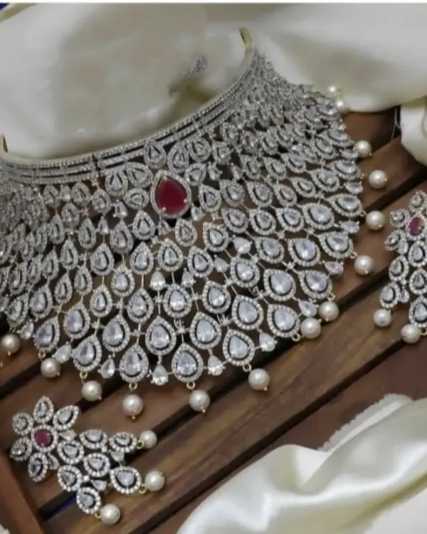 This grand choker set is designed to make a statement. The intricate web of diamond-look stones with a central ruby-red stone and pearl drops is perfect for a reception lehenga or gown.