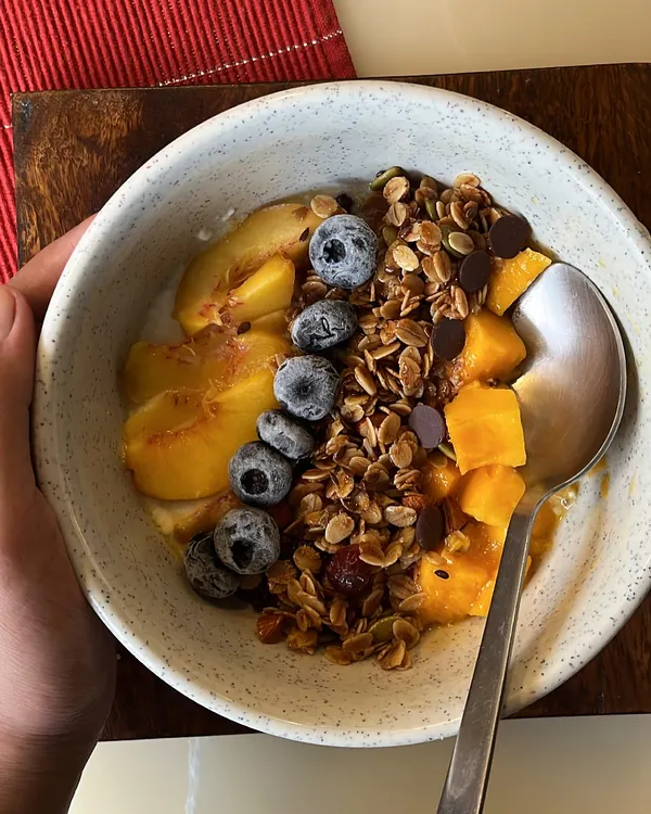 Start your day with a bowl of pure goodness. Our handmade granola, packed with fiber, good fats, and protein, is shown here served with yogurt and fresh fruit for a wholesome and delicious breakfast.