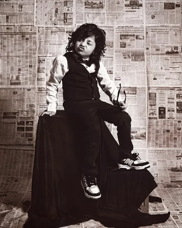 A cool and stylish toddler with great hair, striking a pose with his glasses in our vintage newspaper-themed shoot.