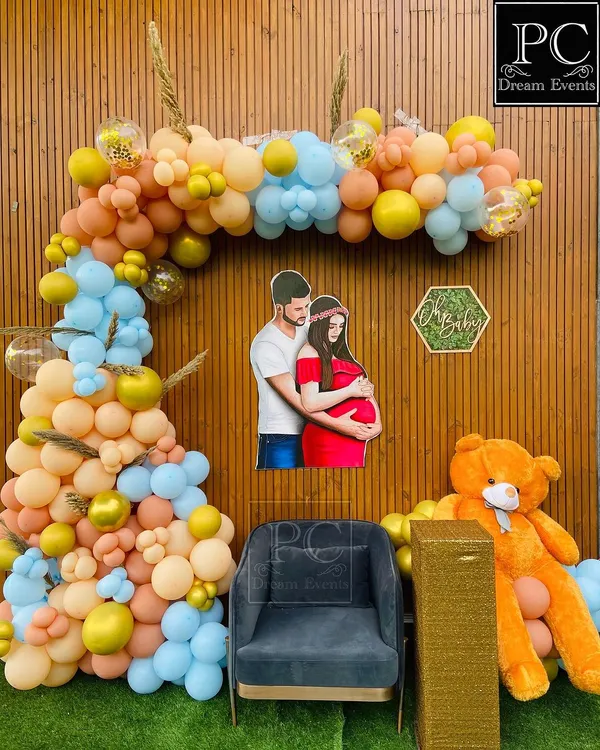 A "We Can Bearly Wait" teddy bear themed baby shower backdrop. A custom cutout of the parents-to-be is the centerpiece, surrounded by a beautiful balloon arch in pastel blue, yellow, and peach.