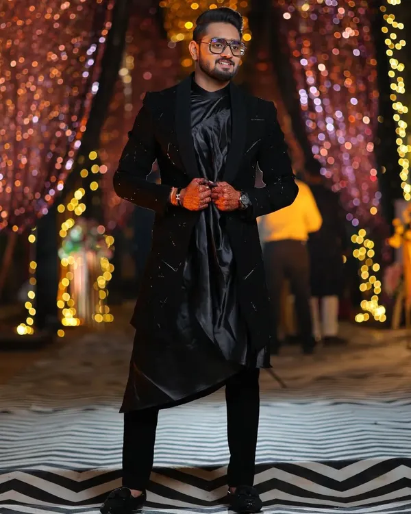 This black open Indo-western is all about layering and texture. The jacket has subtle pipe and katdana work, paired with a black koul kurta and trousers for a complete, modern ethnic look.