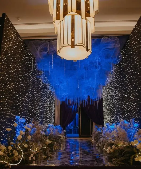 Step into a celestial sangeet through this magical entrance. I designed this passageway with walls of twinkling fairy lights and a ceiling of ethereal blue mesh, creating the feeling of walking through a starry night sky to reach the celebration.