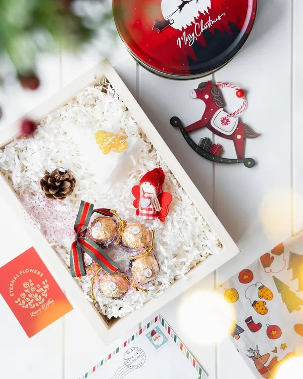 A 'Winter Wonderland' Christmas hamper, featuring a custom tin from Le Meridien Kochi, Ferrero Rocher chocolates, and festive ornaments like a rocking horse and an angel.