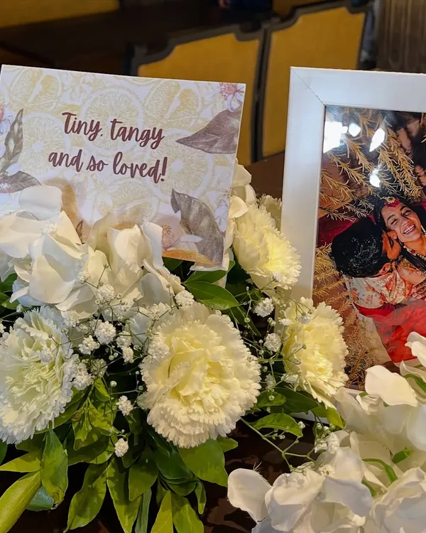 Personal touches make a celebration unique. For this citrus themed shower, a sweet photo of the couple was displayed alongside a custom card reading "Tiny, tangy and so loved," nestled in a bed of white carnations.