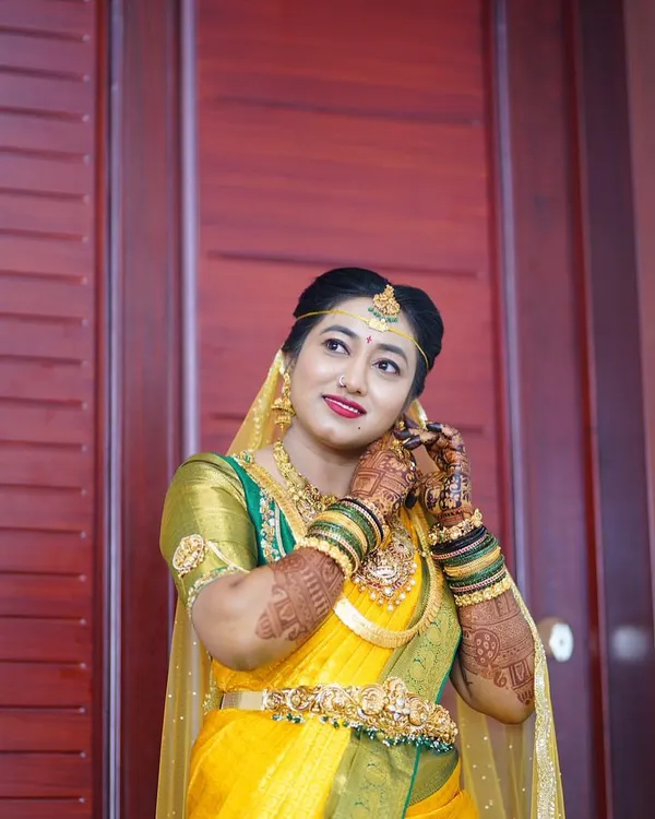 A beautiful South Indian bride in a yellow and green silk saree, her hands adorned with my mehendi. The rich henna stain looks stunning against her traditional gold jewelry.