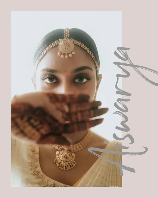 A creative portrait of the bride, Aishwarya, her face partially hidden by her mehendi-adorned hand, drawing focus to her expressive eyes.