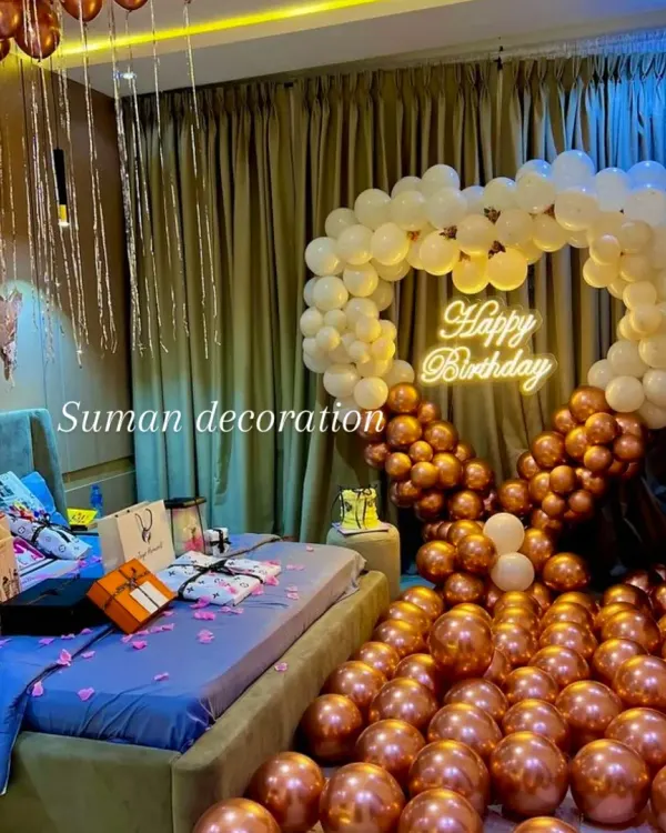 A surprise birthday decoration for a loved one in their bedroom. The setup includes a heart-shaped balloon arch, hundreds of balloons on the floor, and a "Happy Birthday" neon sign for a truly romantic gesture.