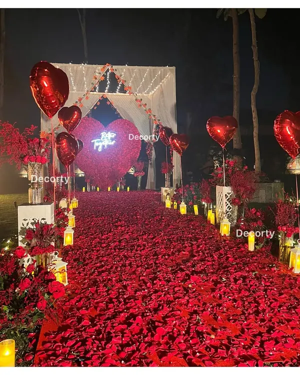 A breathtaking pathway of red rose petals and glowing candles, leading to a canopy for a truly unforgettable proposal night. I design these romantic setups to create a once-in-a-lifetime moment.