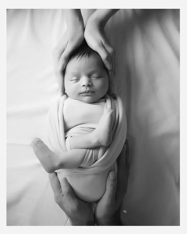 A black and white version of one of my signature shots. The absence of colour makes the loving hands holding the baby even more impactful.