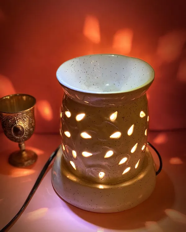 Our electric aroma diffuser creates a warm, inviting glow while filling your room with a relaxing scent. This model features a speckled ceramic finish and teardrop cutouts, casting beautiful light patterns that enhance the calming atmosphere.