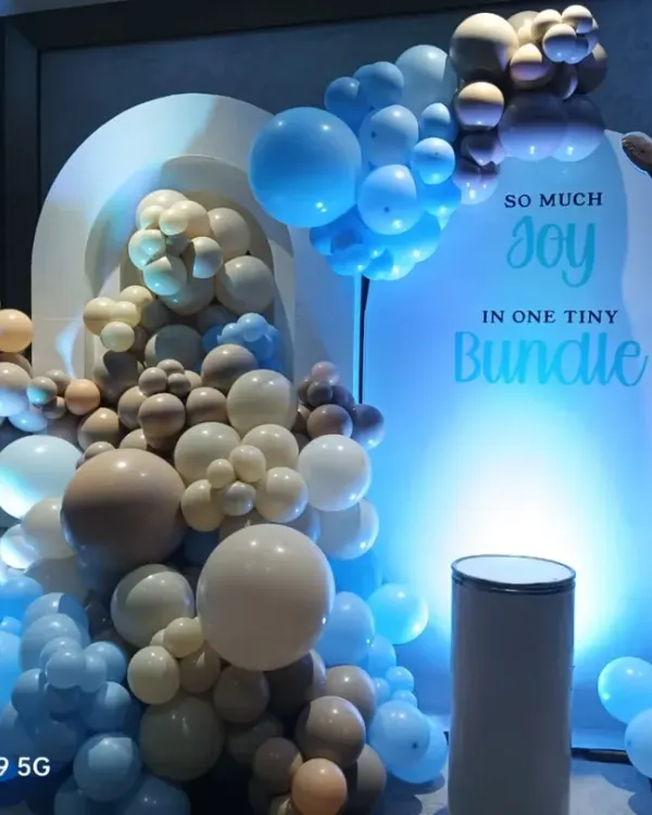 A cute teddy bear theme for a baby boy shower, with the message "So much joy in one tiny bundle". The setup uses a mix of blue, beige, and white balloons with soft lighting to create a warm and inviting look.