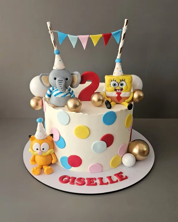 A fun character mashup for Giselle's 2nd birthday. This cake features her favorite fluffy buddies: SpongeBob, Garfield, and a cute elephant, all ready to party.