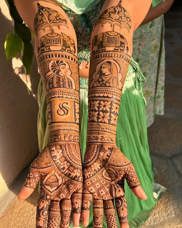 This full-coverage bridal mehendi is a perfect example of telling a love story through henna. It features custom Raja-Rani portraits, the couple's initial 'S', their wedding date, and auspicious elephant motifs, all tied together with intricate patterns.